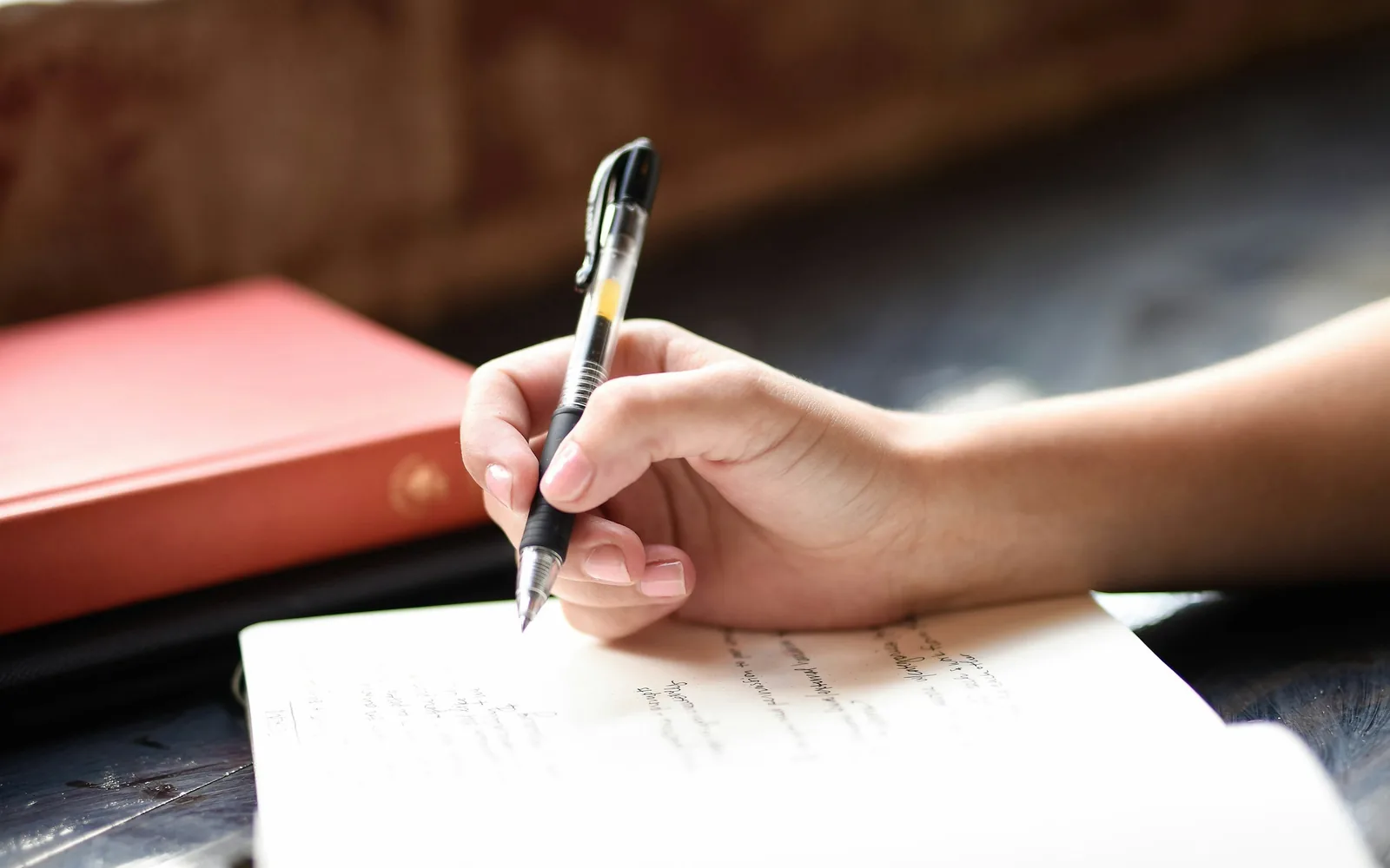 A hand writing in a notebook with a pen.