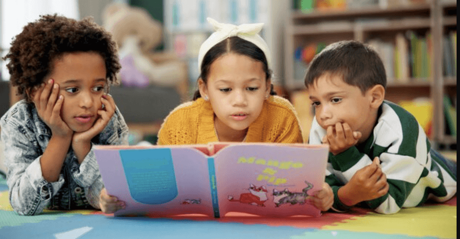 Three pupils reading a picture book together.