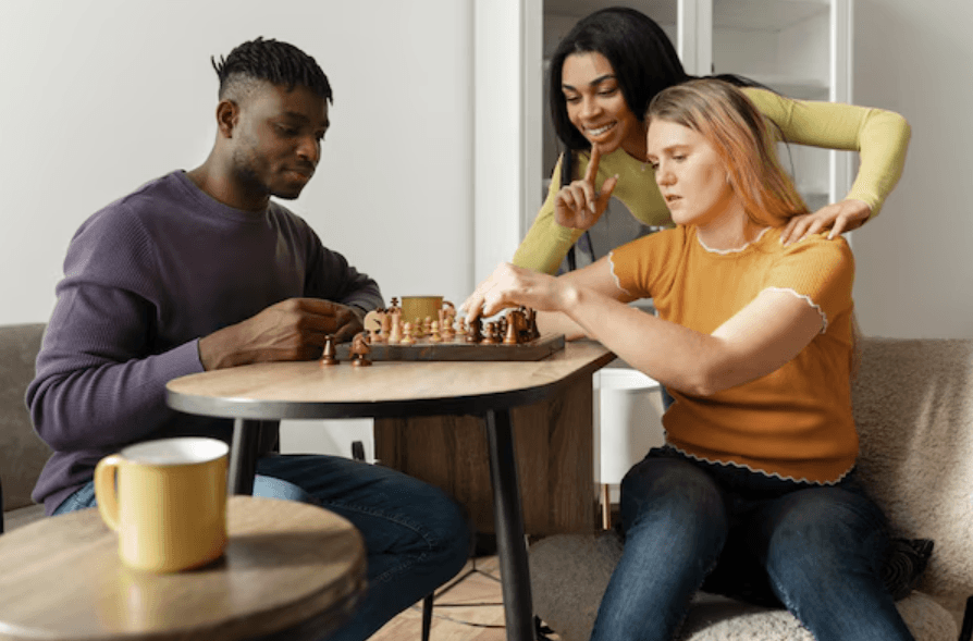 Adults playing chess together at a small table.