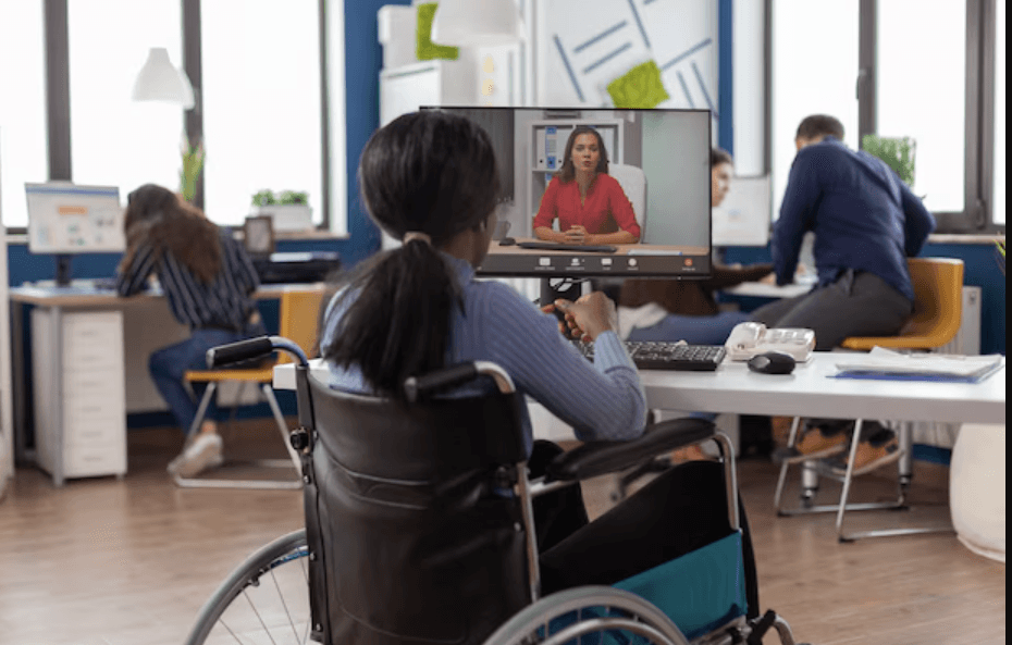 A person who uses a wheelchair takes part in a video call at a desk.