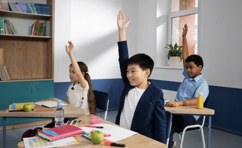Three children raise their hands at their desks in a classroom.