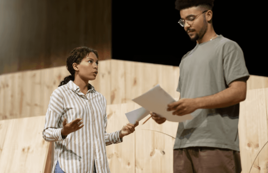 A young speaker and an adult holding notes on a stage.