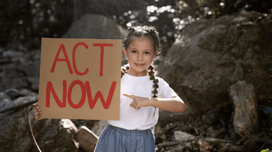 A child holding an ACT NOW sign outdoors.