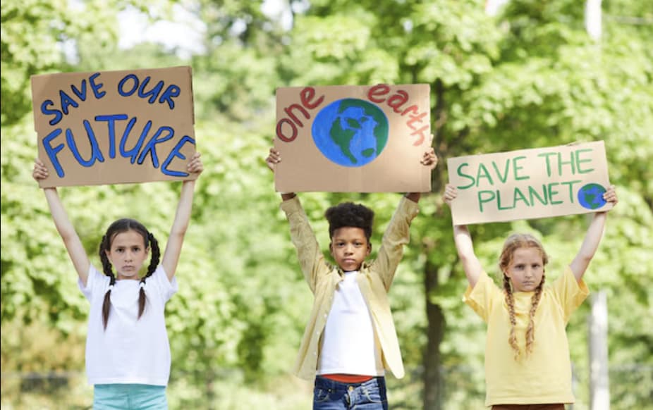 Three pupils holding handmade signs about protecting the planet.
