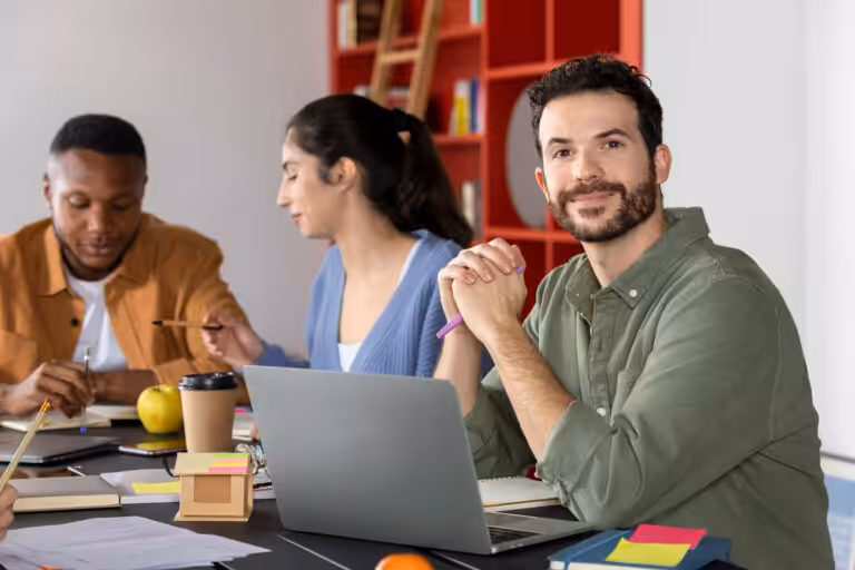 Global collaboration without experience: three diverse teachers working together at a table with laptops and notebooks.